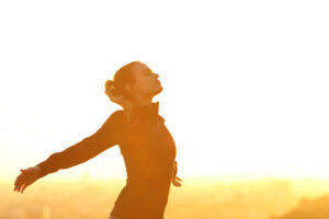 Profile of a runner resting breathing deeply fresh air outstretching arms at sunset