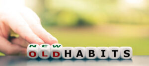 Hand turns dice and changes the expression "old habits" to "new habits".